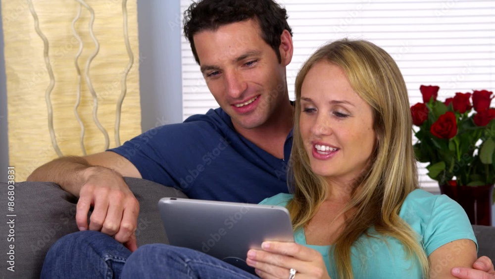 Cute couple using tablet on couch Cute couple using tablet on couch