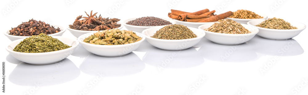 Cardamom, star anise, cinnamon, clove, coriander seed spices and parsley, thyme, rosemary herbs in white bowls Cardamom, star anise, cinnamon, clove, coriander seed spices and parsley, thyme, rosemary herbs in white bowls