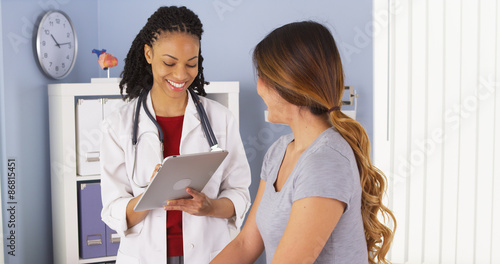Black doctor with tablet talking to female Asian patient photo