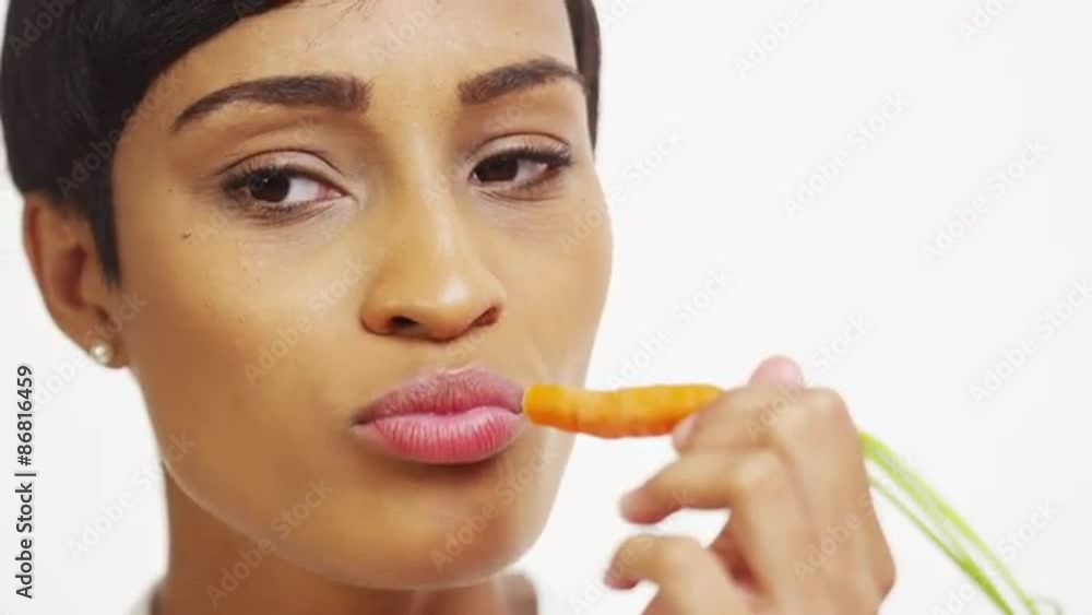 Close up of black woman eating carrot on white background Close up of black woman eating carrot on white background
