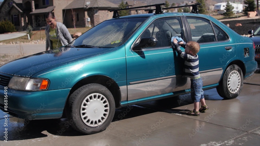 A toddler helping his mother wash car A toddler helping his mother wash car