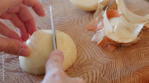 A woman slices an onion on a cutting board photo