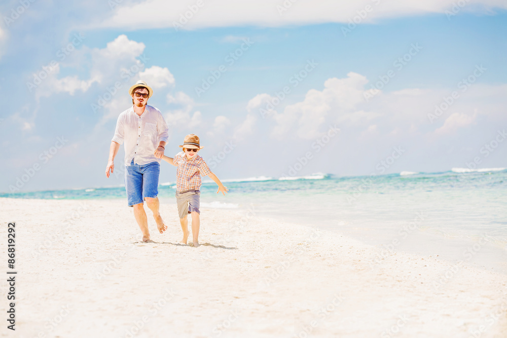 Father with son running barefoot on the sea surf line having