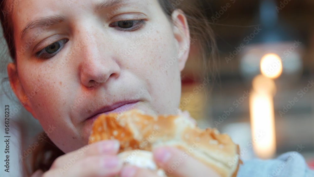A young woman eating fast food burger close up A young woman eating fast food burger close up