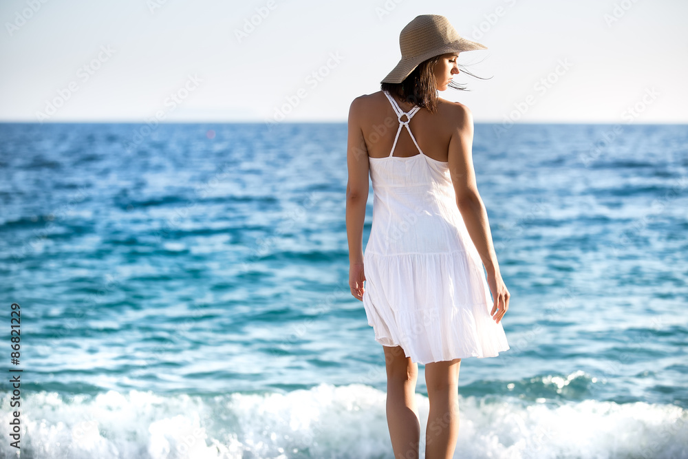 Beautiful woman in a white dress walking on the beach.Relaxed woman breathing fresh air,emotional sensual woman near the sea, enjoying summer.Travel and vacation. Freedom and inspiration concept