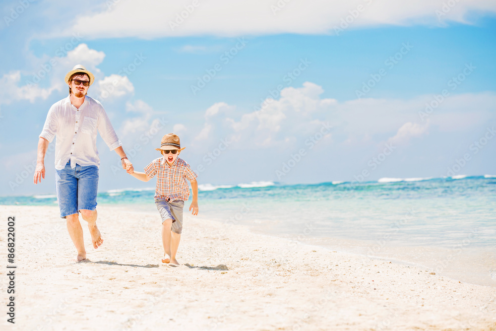 Father with son running barefoot on the sea surf line having Father with son running barefoot on the sea surf line having