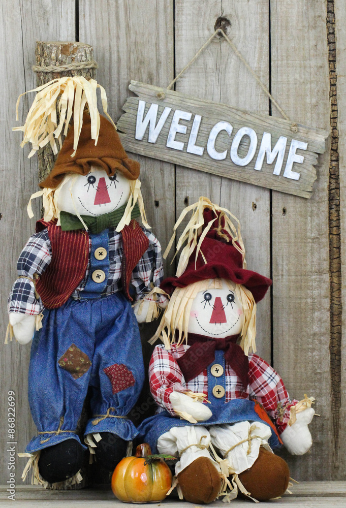 Obraz premium Welcome sign hanging by two scarecrows