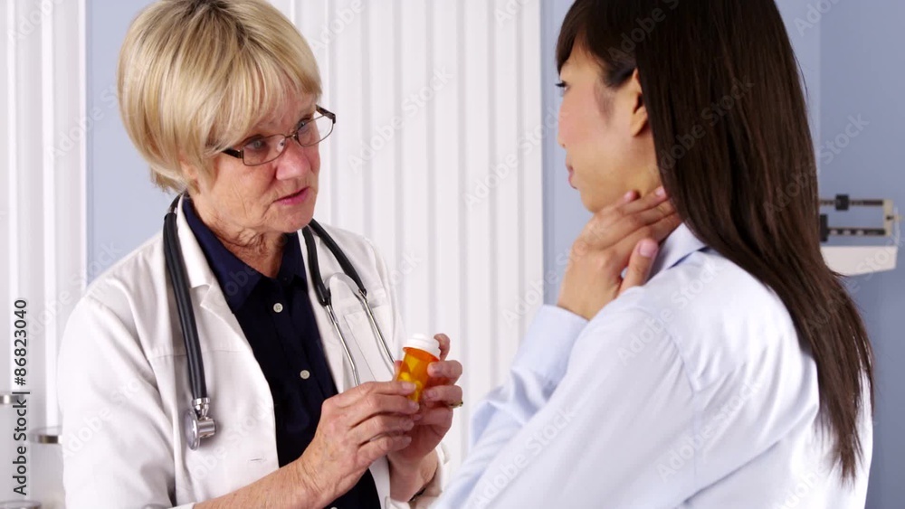 Senior doctor explaining pills to Chinese patient Senior doctor explaining pills to Chinese patient
