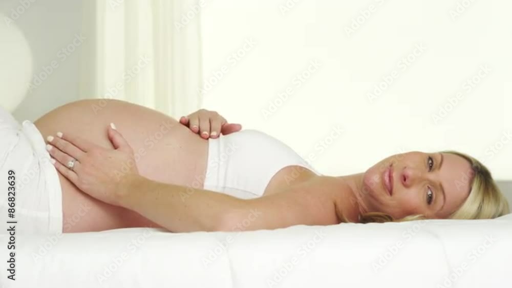 Pregnant woman smiling and resting on bed Pregnant woman smiling and resting on bed