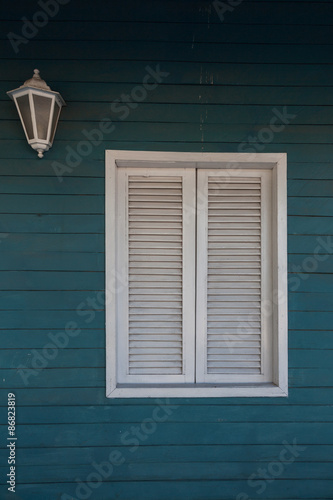 Colonial style. White window on woody wall.