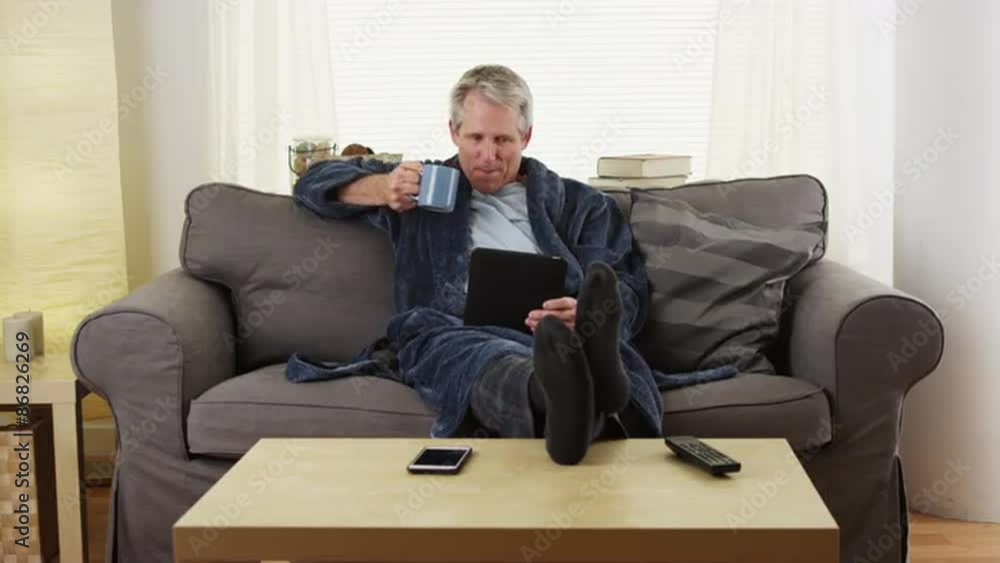 Senior man reading tablet book on couch Senior man reading tablet book on couch