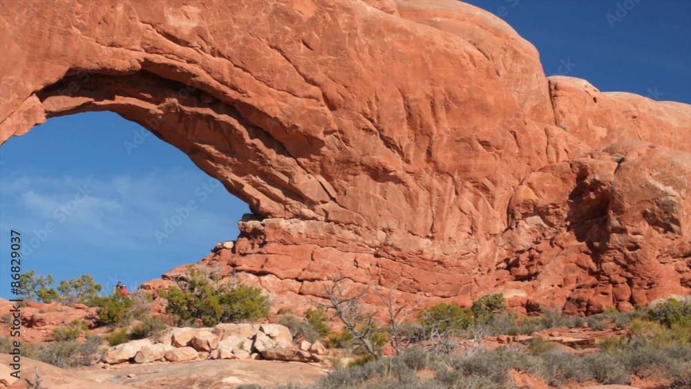 A family hiking below north window arch in Arches National Park A family hiking below north window arch in Arches National Park