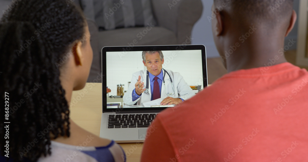 Fototapeta premium Physician talking with young black couple about medical issues over internet video chat