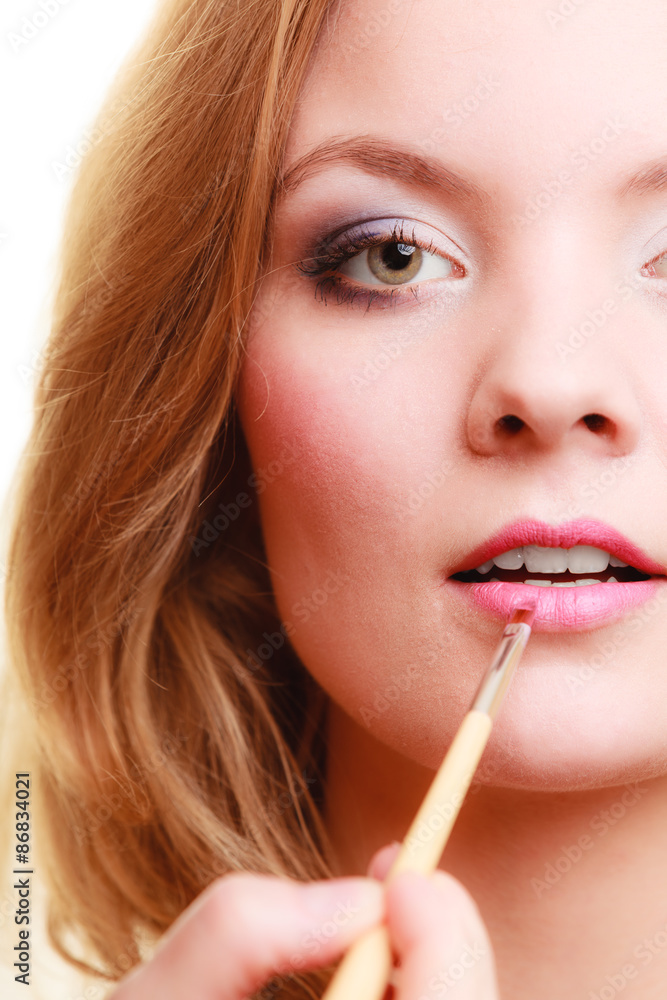 Part of face. Woman applying pink lipstick with brush Part of face. Woman applying pink lipstick with brush