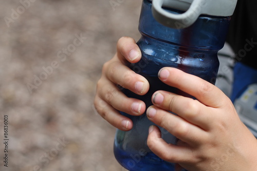 Close up of boy holding water bottle with dirty fingernails