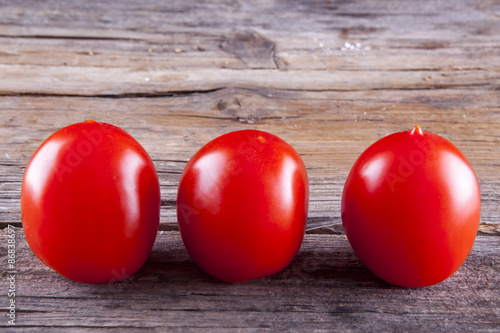 Bunch of tomatoes on vine shot front on on a wooden background