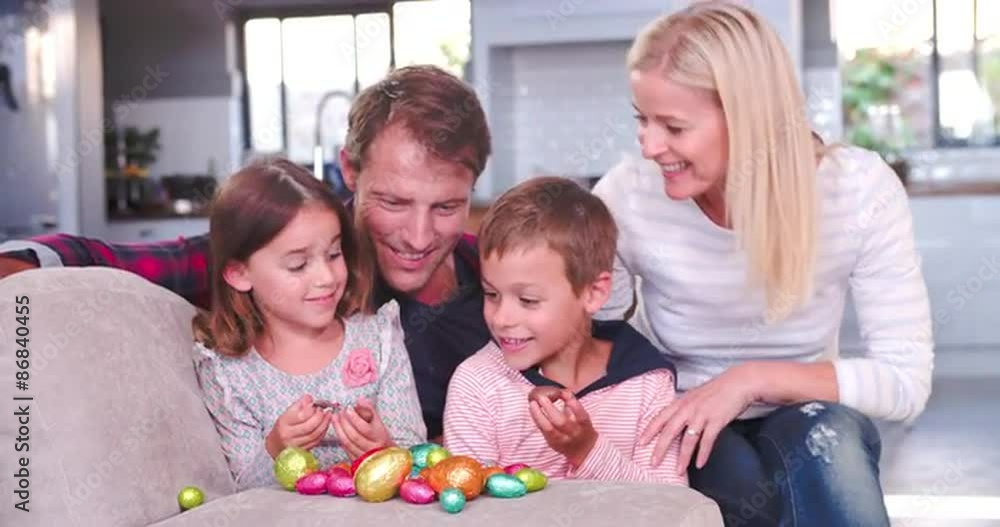 Children Sitting On Sofa With Parents Eating Easter Eggs Children Sitting On Sofa With Parents Eating Easter Eggs