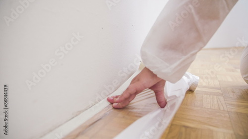 Taping plastic foil to floor close up