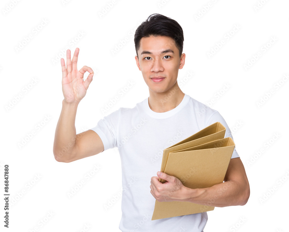 Asian young man hold with folder and ok sign gesture Asian young man hold with folder and ok sign gesture