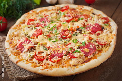 Pizza with salami, tomatoes and mushrooms