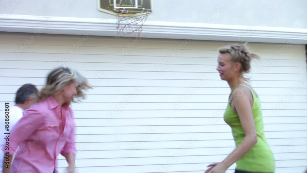 Teenage Family Playing Basketball Outside Garage