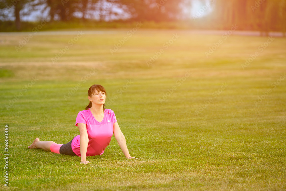 The image with a woman doing yoga in a park The image with a woman doing yoga in a park