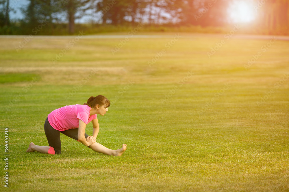 The image with a woman doing yoga in a park The image with a woman doing yoga in a park