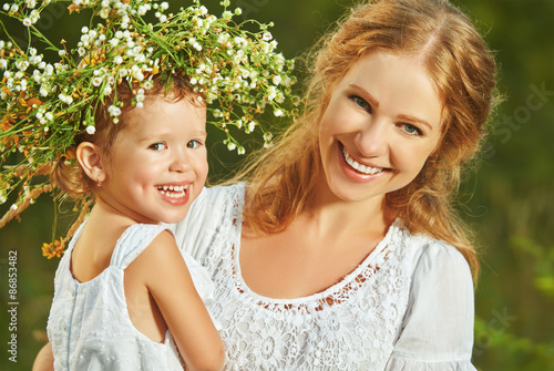 happy laughing daughter hugging mother in wreaths of summer flow