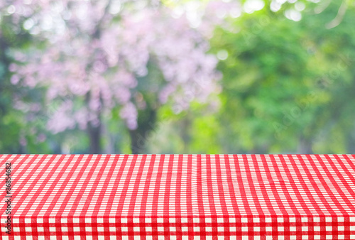 Empty table and red tablecloth with blur green leaves bokeh, for