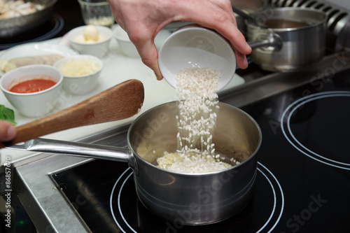 Chef is pouring rice in stewpan photo