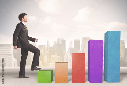 Business person climbing up on colourful chart pillars concept