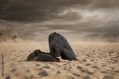 Young businessman hiding head in the sand Fototapet