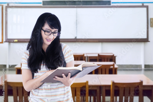 Student standing in class while reading book