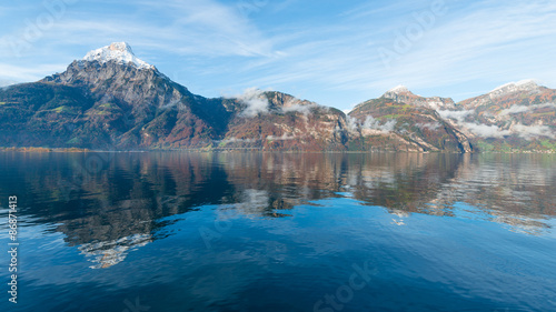 Grandiose panorama of Swiss Alps. Snowy peaks reflected in the lake. 