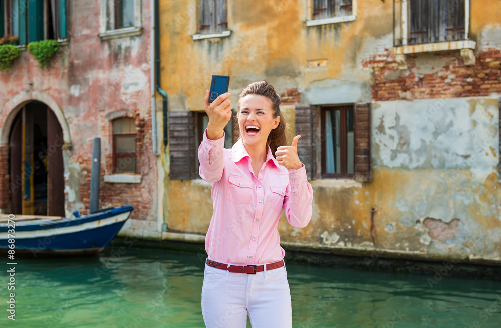 Woman tourist in Venice taking selfie and giving thumbs up