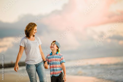 Young happy beautiful mother and her son having fun on the beach