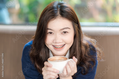 Happy asian smiling female student drinking coffee