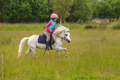 Young girl confident galloping horse on the field Outdoors