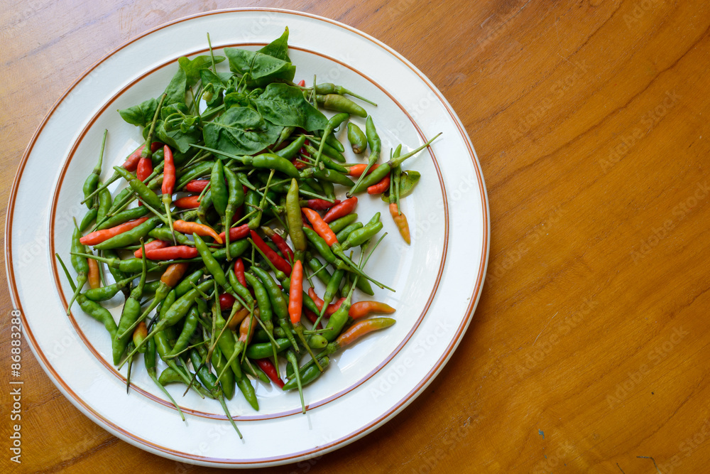 Green, red chili peppers on white dish Green, red chili peppers on white dish