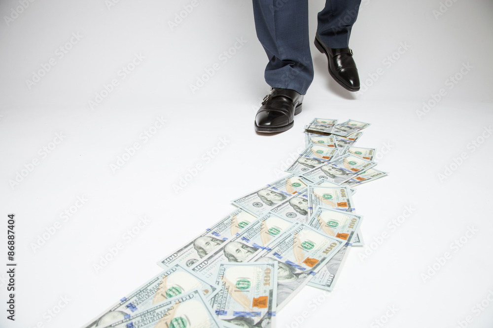 Feet of man in black shoes going by money track