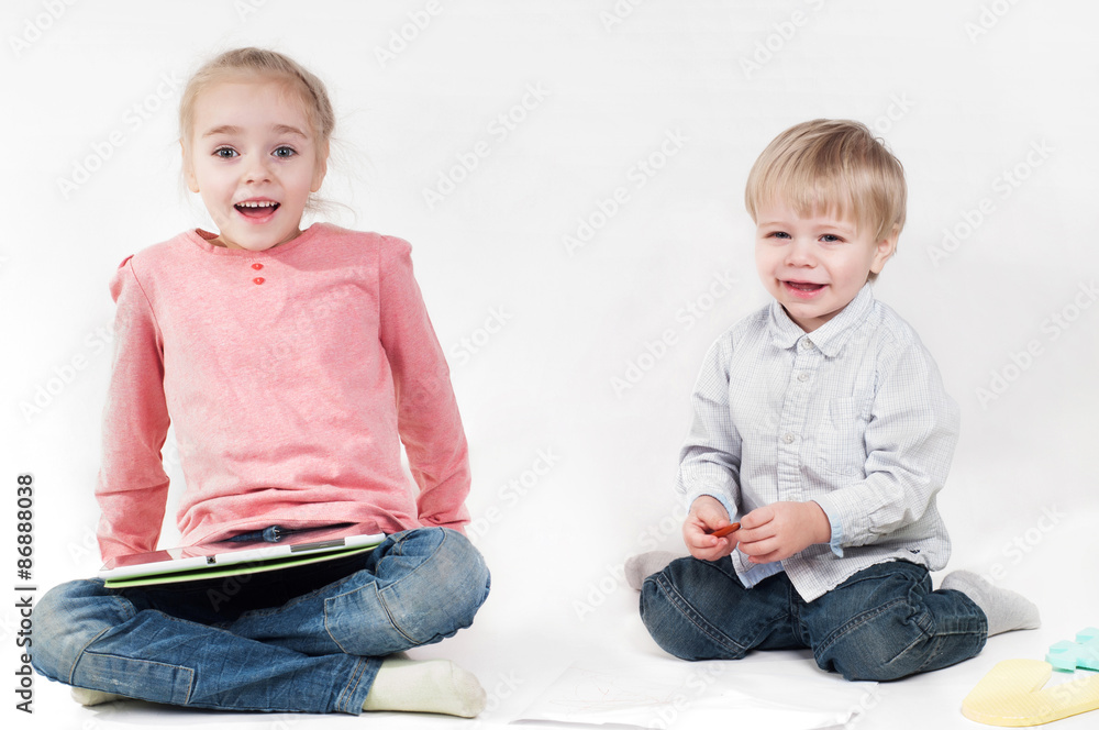 Girl uses a tablet and boy playing with chalk Girl uses a tablet and boy playing with chalk