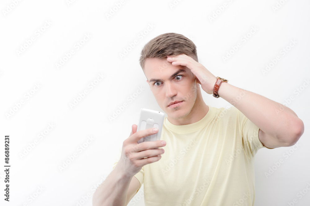 Confused man looking at his mobile phone Confused man looking at his mobile phone