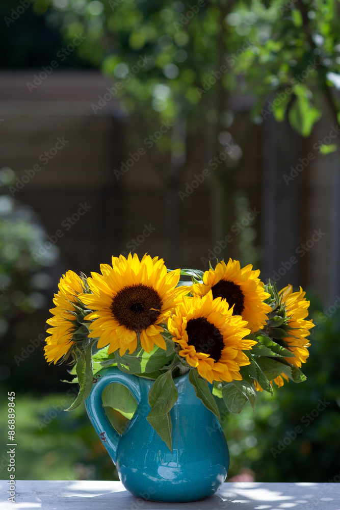 Naklejka premium Bouquet of sunflowers in blue vase in a garden