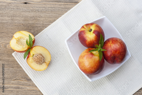 Juicy nectarines in a white plate on the table and slice and nectarines, selective focus
