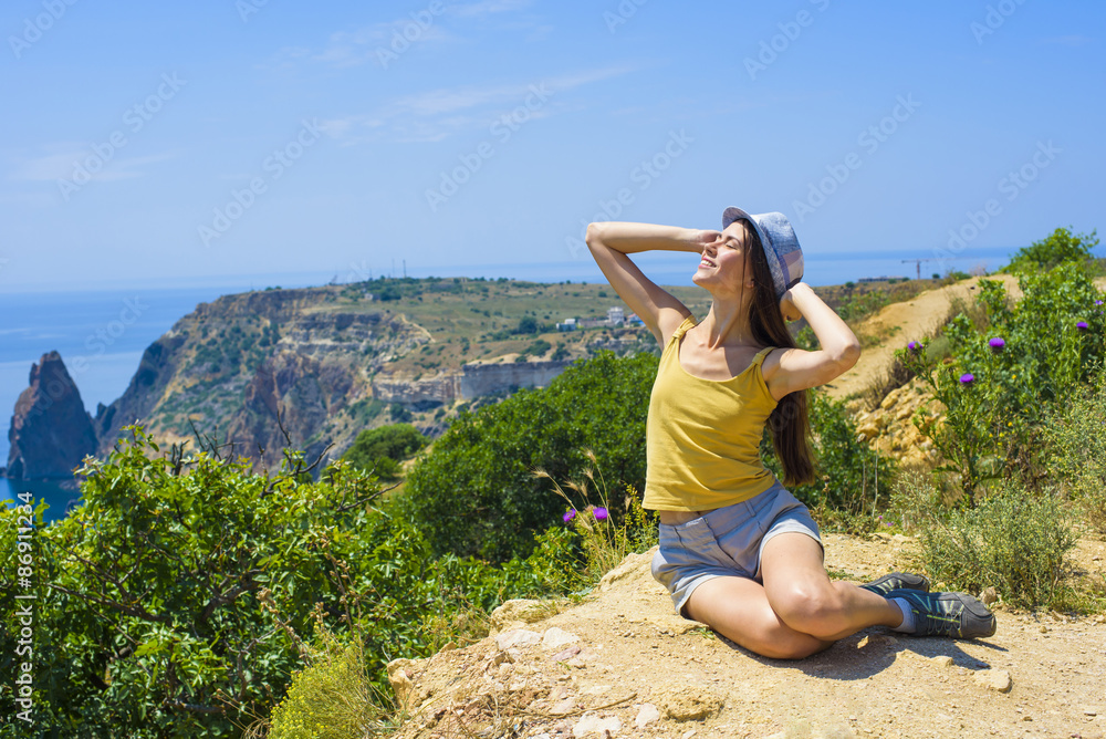young beautiful caucasian female  on a cliff above the sea