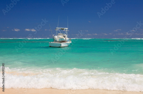 Yacht near the shore of the ocean with small waves andthe blue sky