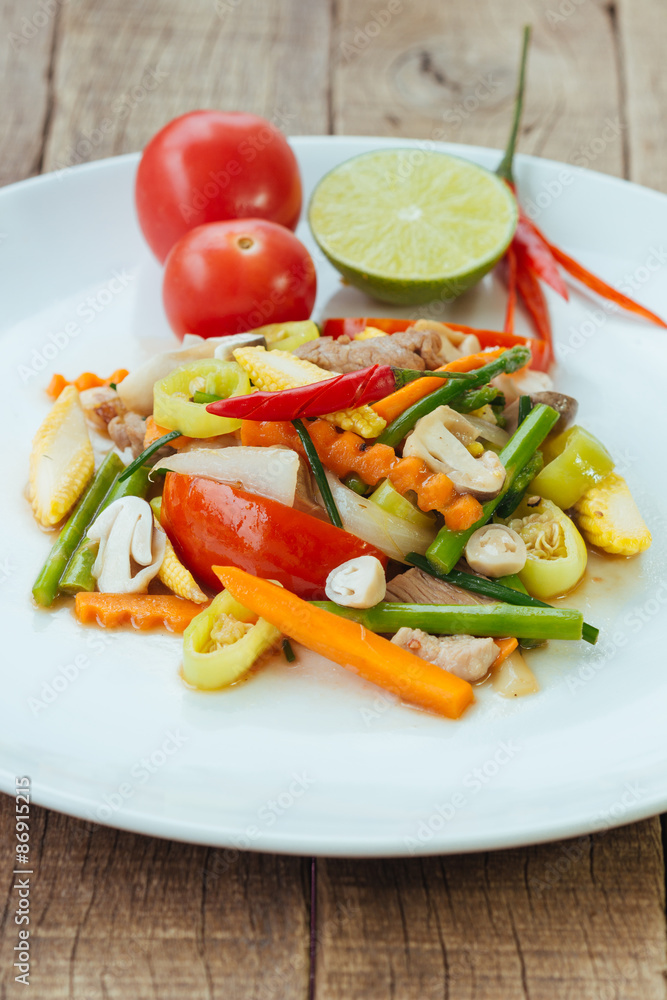 Stir fry vegetables in white dish on wood background