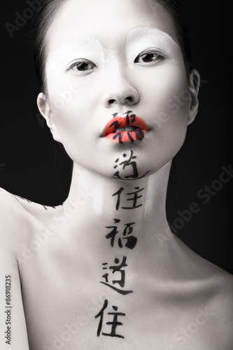 Foto Beautiful Asian girl with white skin, red lips and hieroglyphics