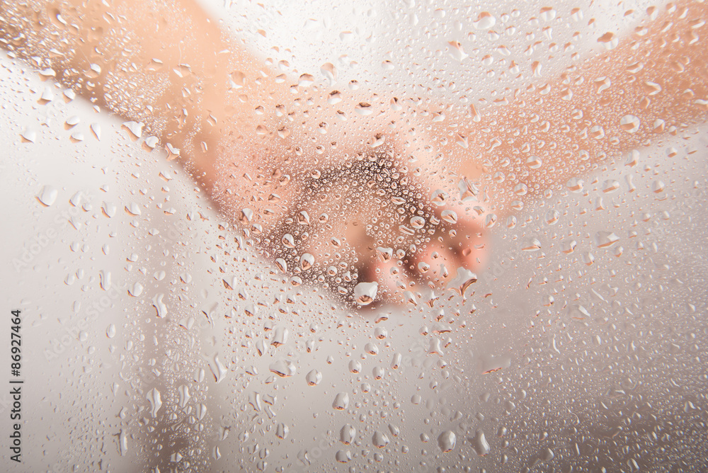 Fototapeta premium Mother's hand holding kid's hand behind the water drop on glass