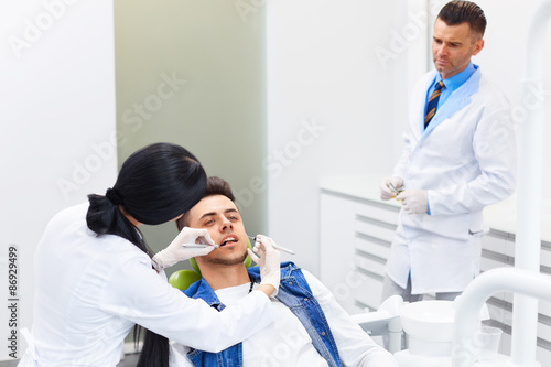 Dentist with Assistant Examining Teeth in the Dentists Chair.